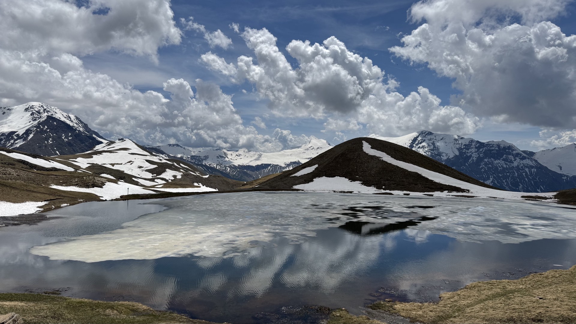 Lac alpin avec reflets des sommets enneigés et cumulus, randonnée altitude Orcières Merlette Hautes-Alpes