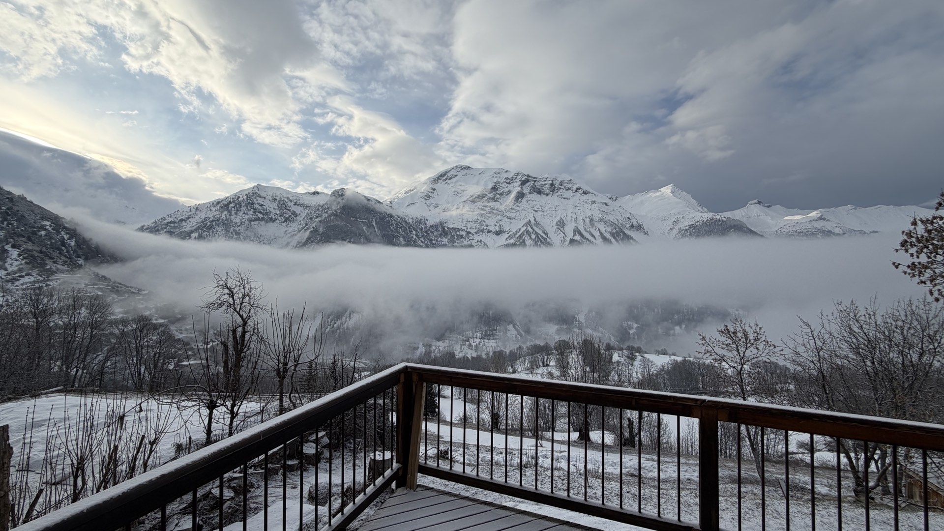 Terrasse du chalet face aux Écrins avec nuages roulant en vallée, hiver Orcières