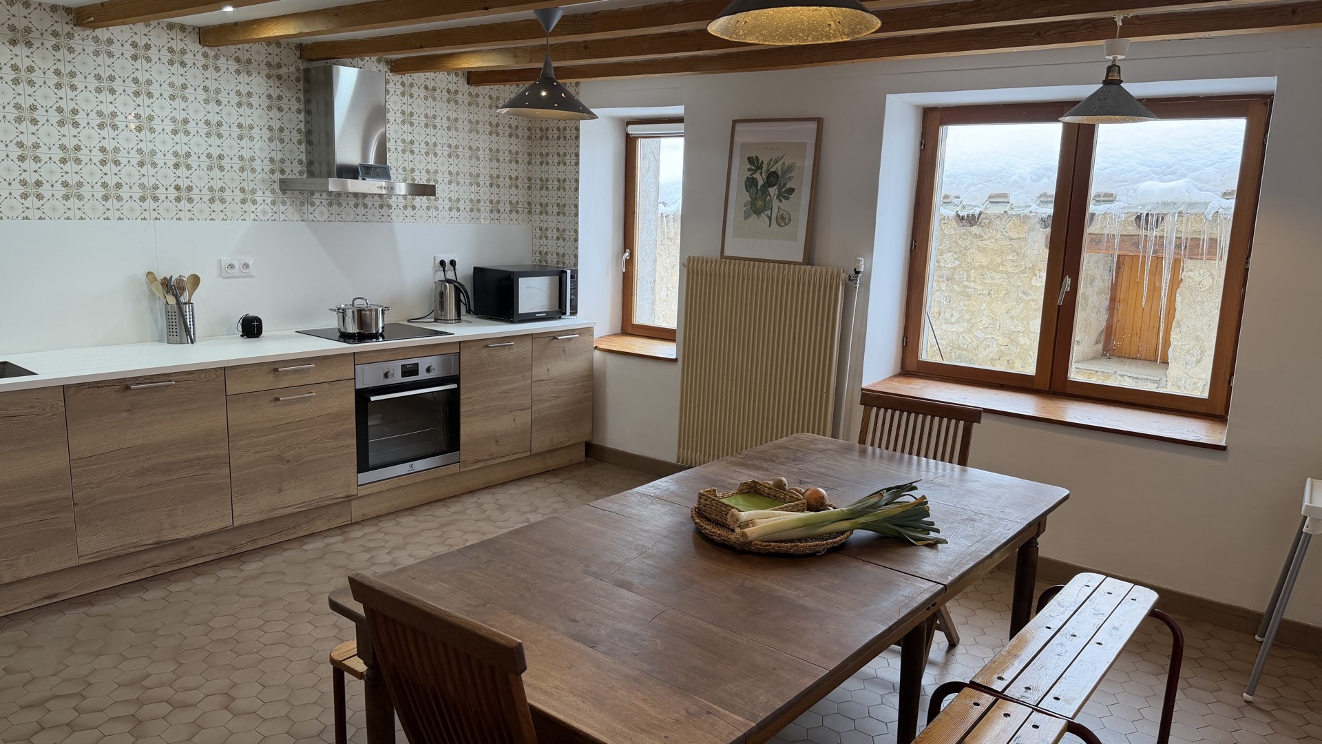 Grande cuisine équipée avec poutres apparentes, table en bois massif et vue montagne, chalet des Écrins Orcières Merlette
